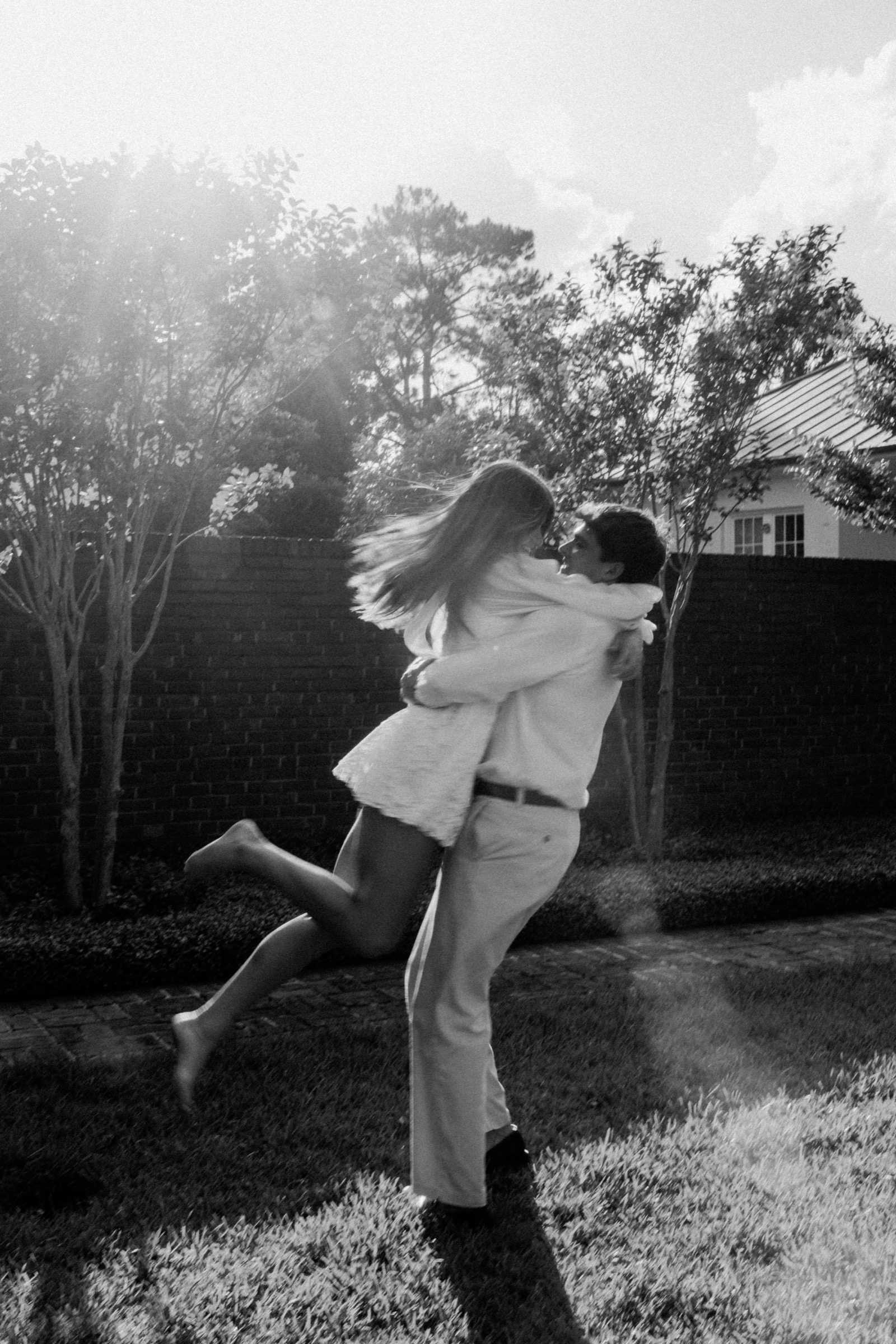 Black and white engagement portrait of Sage and Will embracing outdoors