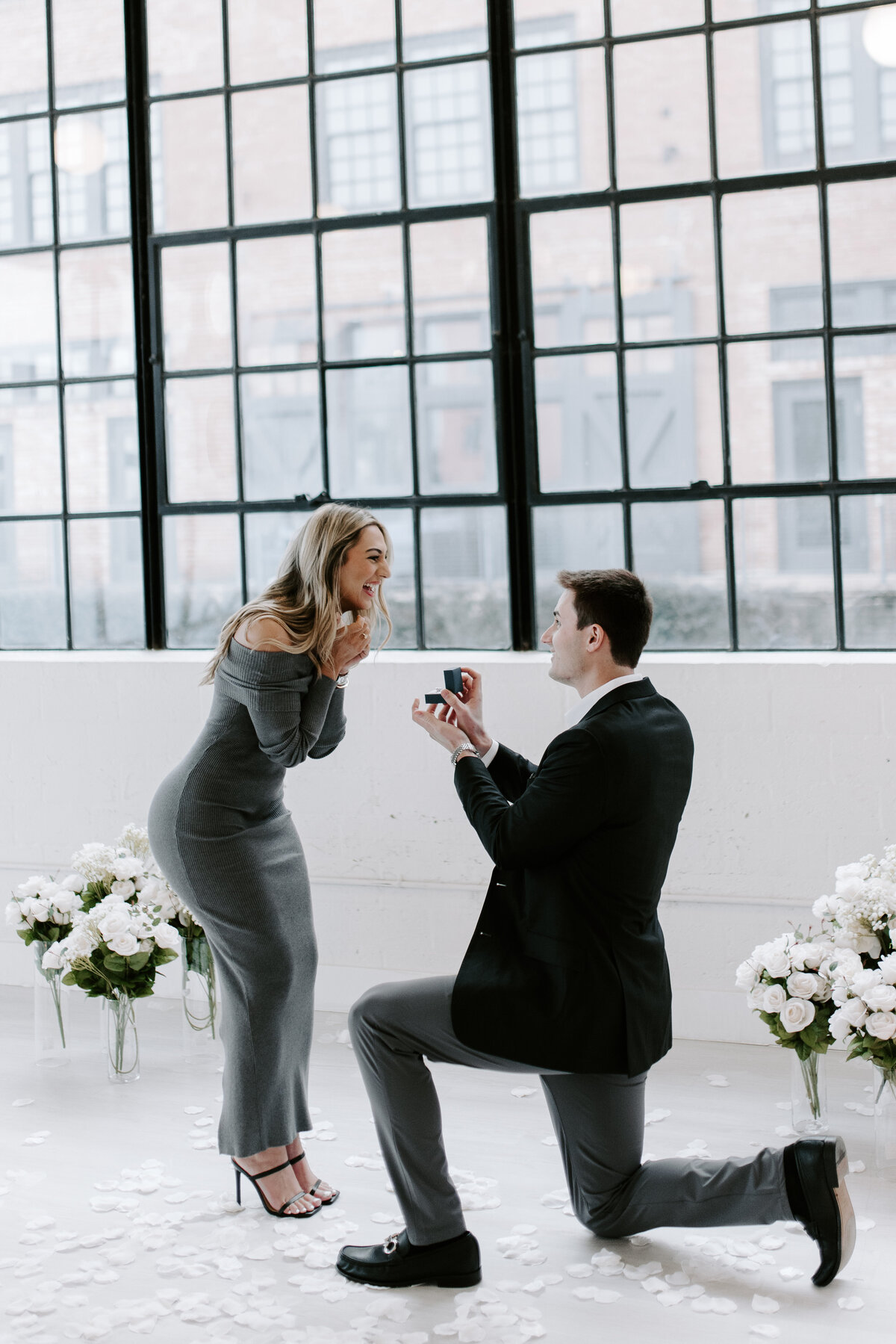 A surprise proposal in a bright room with tall windows